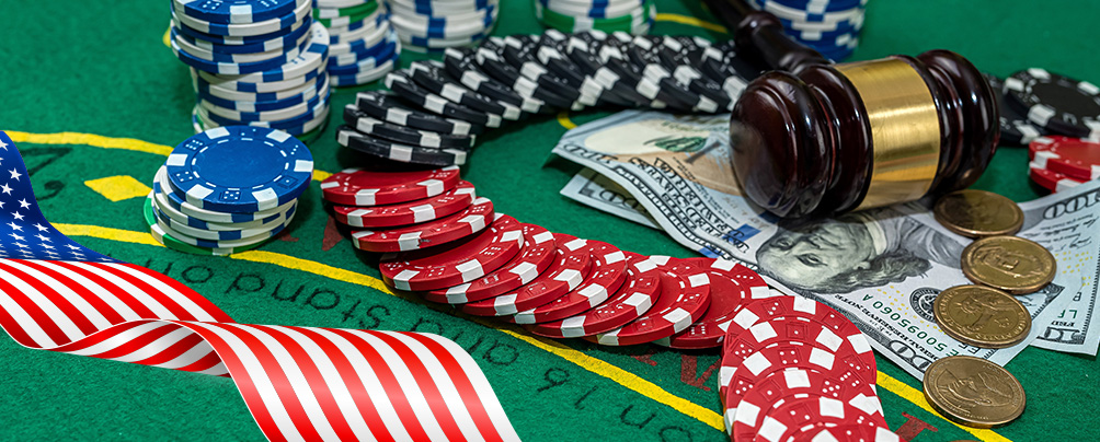 Casino table with scattered chips, paper money and coins, a judge's gavel and the US flag