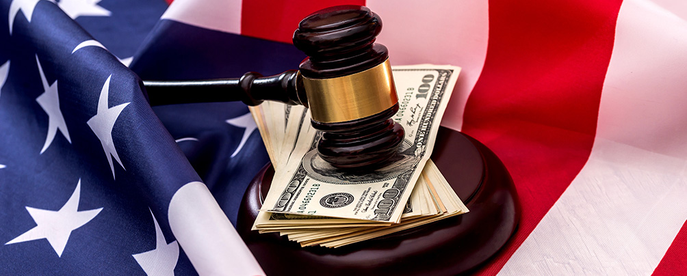 A judge's gavel on a stack of $100 bills with an American flag