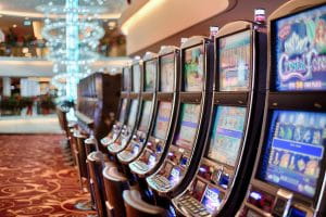 Video slot machines inside a casino with a red carpet containing a busy golden pattern.