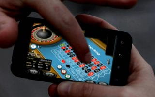 A gambler playing a game on his smartphone.