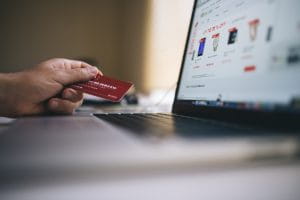 Man's hand holding credit card while online shopping on a laptop computer