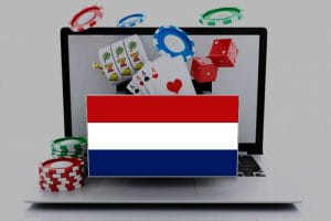 The Flag of the Netherlands in front of a laptop that represents online gambling, with chips, cards, and slot reels