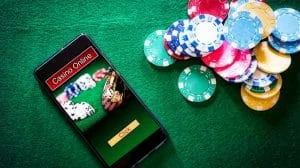 Smartphone with online casino imagery on the felt of a betting table next to poker chips
