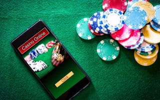 Smartphone with online casino imagery on the felt of a betting table next to poker chips