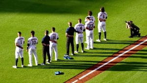 Houston Astros players wearing their home white uniforms stand on the baseball field during the National Anthem