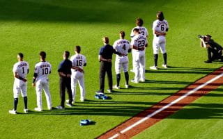 Houston Astros players wearing their home white uniforms stand on the baseball field during the National Anthem