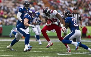 Two defensive players from the NFC wearing blue uniforms converge to tackle the ball carrier of the AFC wearing white in the NFL Pro Bowl.