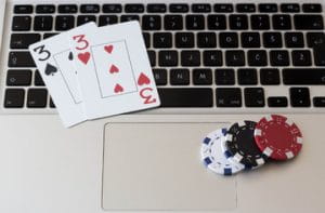 A pair of threes and four poker chips on a MacBook keyboard to represent online poker.