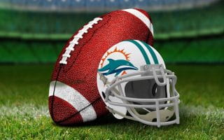 A white Miami Dolphins helmet featuring the teal dolphin, teal stripe, orange splash, and white facemask next to a football