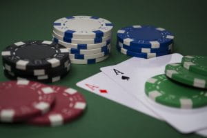 Stacks of poker chips on a pair of Aces on the green felt of a poker table to represent online gambling.