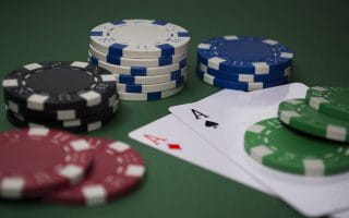 Stacks of poker chips on a pair of Aces on the green felt of a poker table to represent online gambling.