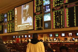 Man in hooded sweatshirt looking up at the NFL football sportsbook numbers.