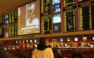 Man in hooded sweatshirt looking up at the NFL football sportsbook numbers.