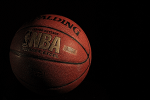 An official NBA orange leather basketball with gold lettering and a black backdrop.