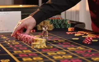 A man picking up poker chips in a casino