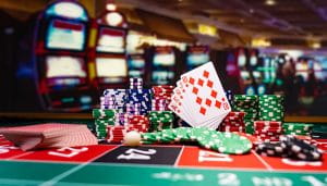 Cards and Poker Chips Over a Roulette Table in a Casino with Blurry Slots in the Background 