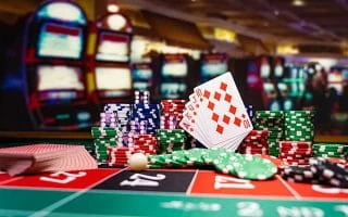 Cards and Poker Chips Over a Roulette Table in a Casino with Blurry Slots in the Background