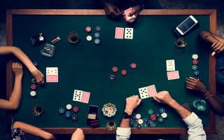 A Shot Over a Table Where Five People Are Playing Poker