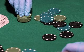 Casino Chips Handled with Gloves Next to Casino Cards on a Poker Table