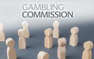 Gambling Commission Logo Over Wooden Figurines