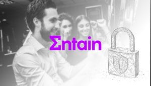 Entain Logo Next to a Padlock on a Blurry Casino Hall Background