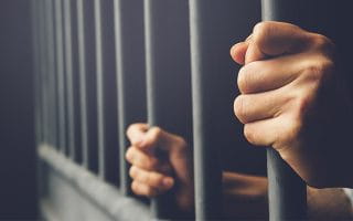 A Prisoner Holding the Bars of a Cell with Bare Hands