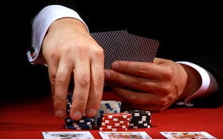 Poker Player Holding Cards and Chips at a Casino Table 