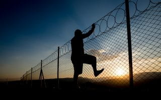 A Person Climbing Prison Fence in Attempt to Escape