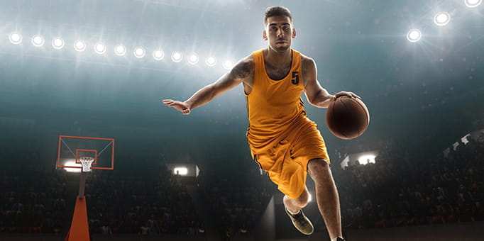 Man playing basketball in a college uniform.