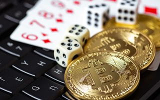 Bitcoin Coins with Casino Dice and Cards on a Laptop Keyboard
