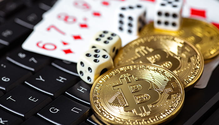 Koin Bitcoin dengan Dadu Kasino dan Kartu di Papan Ketik Laptop