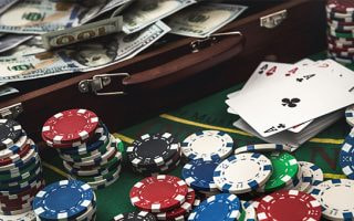 An image including cash, casino chips and cards.