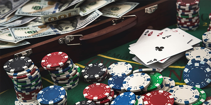 An image including cash, casino chips and cards. 