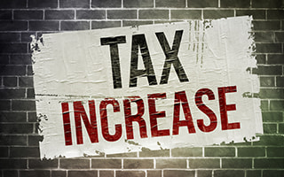 Tax increase wording painted on a brick wall
