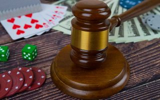A judge’s hammer next to cards and dice